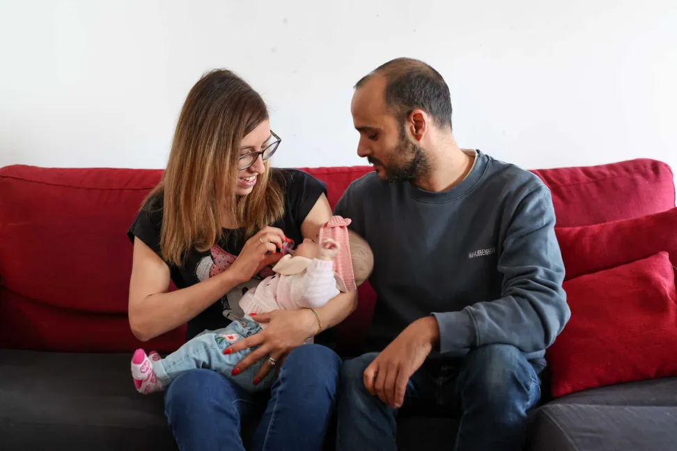 Bebé ao colo da mãe com o pai ao lado