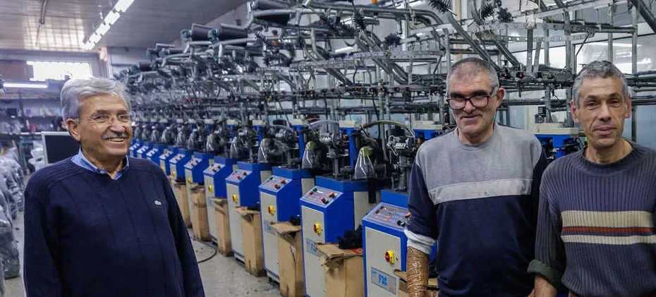 Patrão e dois funcionários numa fábrica de meias