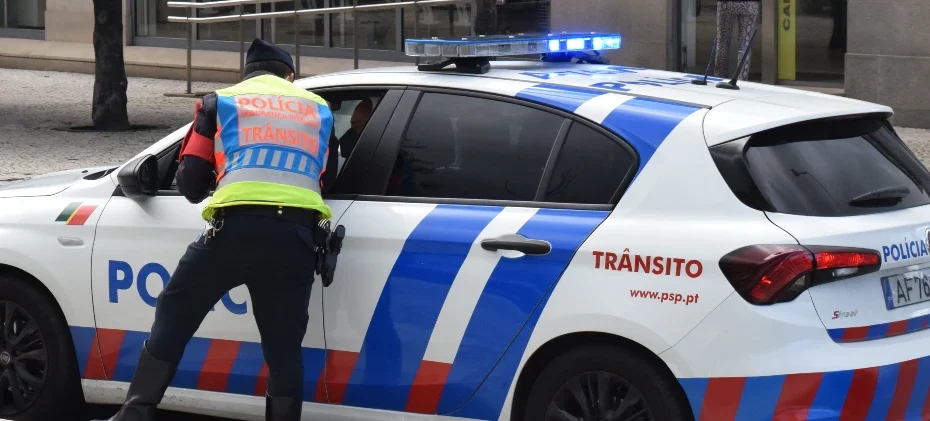 Agente da PSP junto do carro da polícia